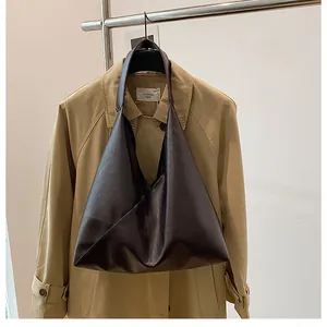 Detail of the soft dark brown vintage tote bag hanging against a classic trench coat