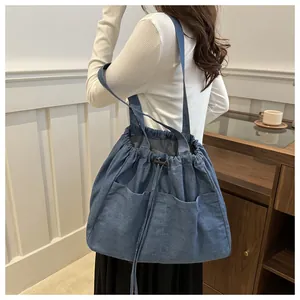 Deep blue denim tote bag with drawstring closure and multiple front pockets on model