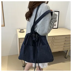 Detail view of large dark blue denim tote bag with functional drawstring closure and pockets