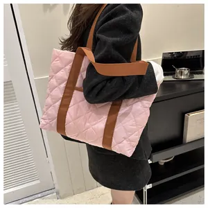 Detail of light pink quilted tote bag with brown handles in an office setting