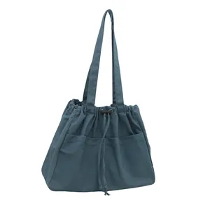 Large denim drawstring tote bag with dual front pockets for women's daily commute
