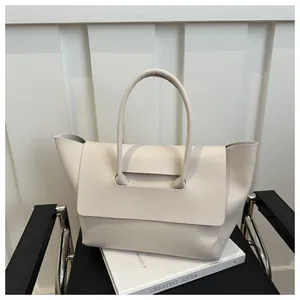 Detail van een beige mat leren shopper op een boek voor een minimalistische uitstraling