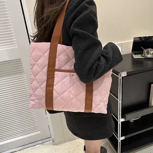 Pink quilted tote bag with brown straps shown on shoulder for a stylish casual look