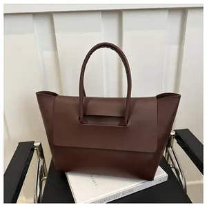 Detail van donkerbruine leren shopper tas met handvatstructuur en klepsluiting detail