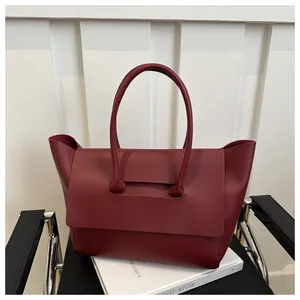 Detailopname van de donker bordeauxrode leren tas met unieke trapezevormige flap