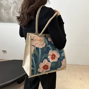 Bolso tote con estampado floral artístico y asas de cuerda trenzada usado por modelo