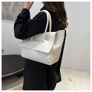 Detail van een minimalistische witte draagtas met gladde afwerking en lange hengsels