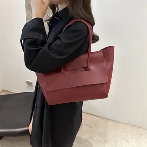 Minimalistische bordeauxrode grote shopper tas van zacht leer getoond op een model
