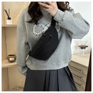 Detail of minimalist black canvas chest bag with metallic zipper and triangular puller