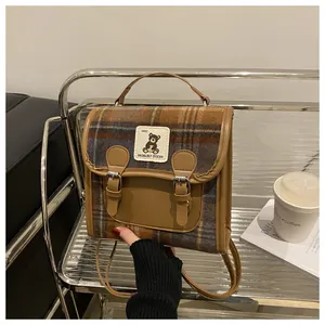 Detailed view of British vintage plaid backpack with brown leather trim and bear patch