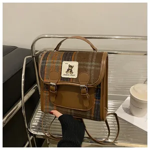 Detail of vintage plaid backpack showing bear patch and premium leather handles