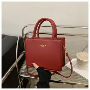 Detail of red leather crossbody bag with golden hardware and fashion lettering