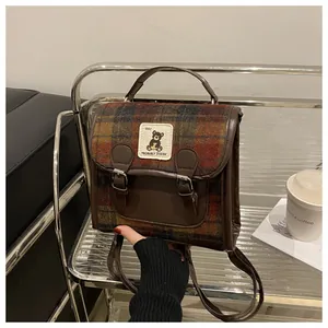 Detail of British plaid backpack with leather straps and cute cartoon bear patch
