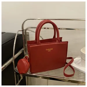 Close-up of red PU leather handbag with gold hardware and small round coin purse on a shelf