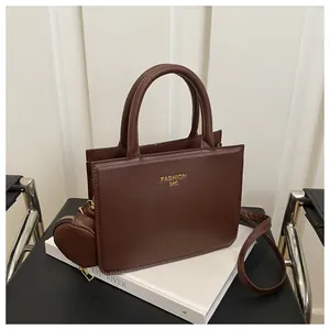 Detail of a brown crossbody bag set with gold Fashion Bag lettering and small pouch
