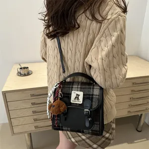 Retro British style plaid backpack with plush bear charm shown from a side view