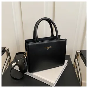 Detail of black PU leather tote bag with gold lettering and small round coin purse charm