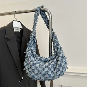 Blue checkerboard denim hobo bag with frayed edges and wide shoulder strap