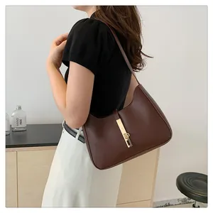 Detail of a dark brown crescent bag with a gold metal clasp and adjustable shoulder strap