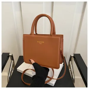 Detailed view of brown PU leather square handbag with gold lettering on elegant background