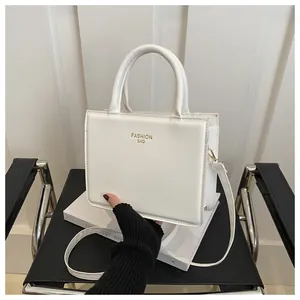 Detail of white square PU leather handbag with golden Fashion Bag text and metal hooks