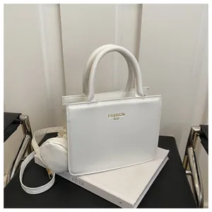 Detail of white rectangle handbag with round handle and matching round coin purse charm