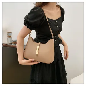 Detail of elegant beige crescent hobo bag featuring gold metal buckle and leather strap