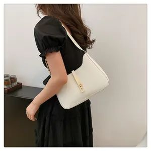 Close-up of white leather hobo bag featuring a sleek gold metal buckle on shoulder strap