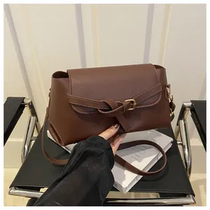 Gros plan sur le sac bandoulière marron avec boucle à nœud décorative et rabat élégant