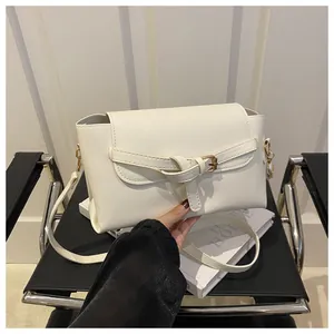Détail du sac bandoulière en cuir blanc avec sangle nouée unique et ferrures dorées