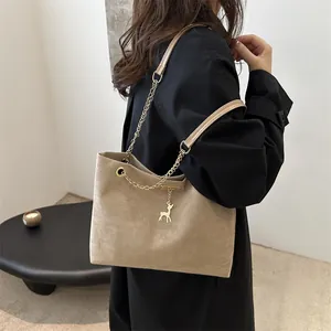 Sac fourre-tout vintage en daim beige avec chaîne dorée et pendentif cerf sur manteau