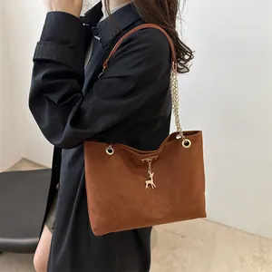 Sac sous le bras en daim marron vintage avec chaîne dorée et pendentif cerf sur modèle