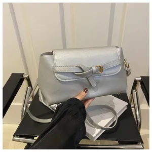 Détail d'un sac bandoulière argenté métallisé avec boucle à nœud sur une chaise design