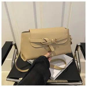 Détail d'un sac bandoulière beige avec boucle décorative dans un décor minimaliste