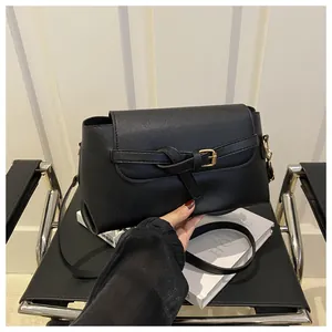 Détail du sac bandoulière en cuir mat noir avec nœud décoratif et boucle en métal doré