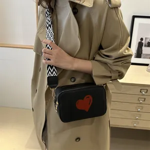 Minimalist black leather crossbody bag with red heart pattern and geometric strap