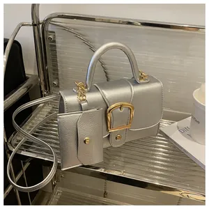Detail van zilveren crossbodytas met gouden gesp en bijpassende kleine portemonnee