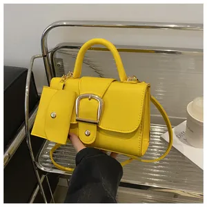 Detail van gele tas met lycheestructuur, gouden hoefijzergesp en extra klein tasje