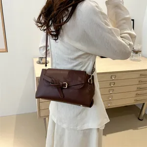 Sac bandoulière marron foncé vintage avec boucle porté à l'épaule pour un look élégant