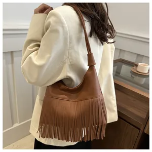 Deep brown leather fringe shoulder bag shown with a corduroy blazer for a bohemian style