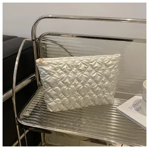 Detailed view of white quilted heart pattern makeup bag with a gold metal zipper