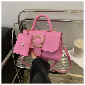 Detail van felle roze crossbodytas met gouden gesp en een mini-muntportemonnee