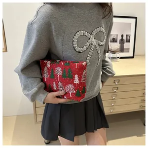 Close-up of a festive red Christmas tree pattern toiletry bag held in a model's hand