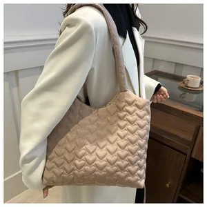Détail du sac fourre-tout beige avec matelassage en cœur montrant sa texture douce