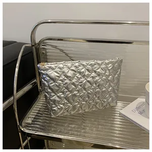 Detail of silver heart-quilted cosmetic bag with gold zipper on modern display shelf