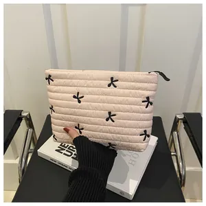 Detail of pink quilted makeup bag featuring black bow embroidery and smooth zipper
