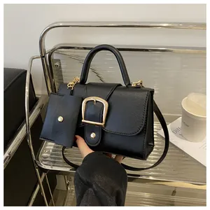 Detail van zwarte leren tas met textuur, gouden gesp en extra mini portemonnee
