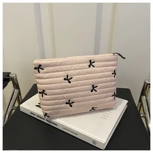 Detail of pink quilted cosmetic bag with black embroidered bows on a book