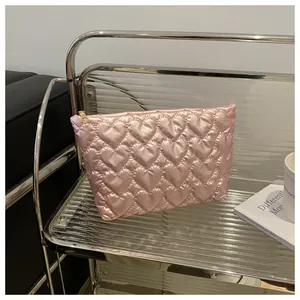 Detailed view of pink quilted fabric with heart pattern and golden zipper closure