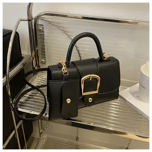Detail van zwarte crossbody tas met gouden gesp en klein muntzakje aan de zijkant